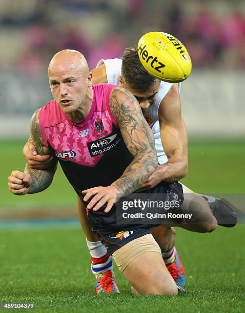 Nathan Jones of the Demons handballs whilst being tackled by Daniel Giansiracusa of the Bulldogs during the round eight AFL match between the...