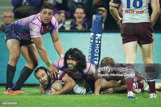 Brett Stewart of the Eagles looks up after being tackled by Young Tonumaipea Tohu Harris and Kurt Mann of the Storm during the round nine NRL match...