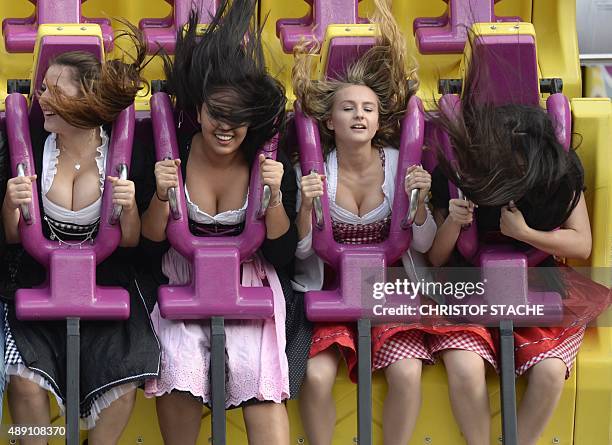 Young women in traditional Bavarian Dirndl dresses enjoy a ride on a roller coaster at the Theresienwiese fair grounds of the Oktoberfest beer...