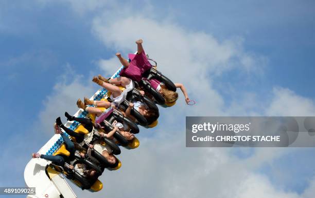 Visitors sit in a fairground ride at the Theresienwiese fair grounds of the Oktoberfest beer festival in Munich, southern Germany, on the festival's...
