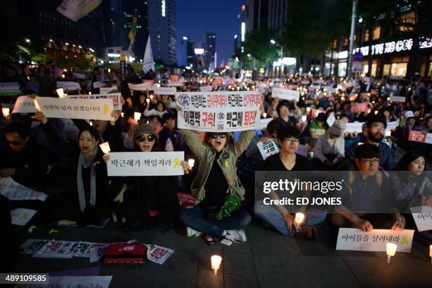 People shout slogans as they hold placards reading 'Your fault, President' and 'down with friends of Lee Myung Bak' during a rally paying tribute to...