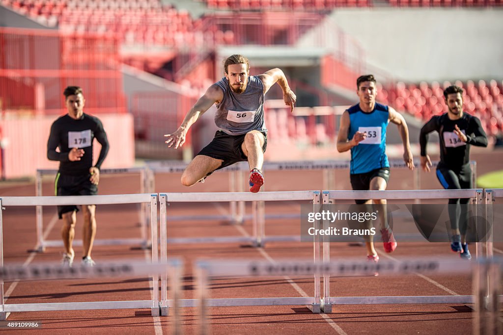 Masculinos jóvenes atletas salto obstáculos en una carrera.