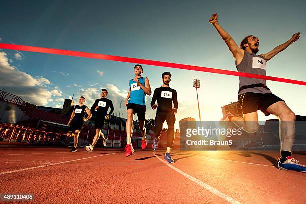 erfolgreiche sportlerin überqueren der ziellinie und gewinnt das rennen. - marathon stock-fotos und bilder
