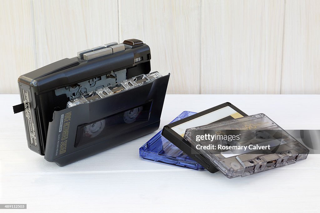 Outdated audio recorder and cassettes on white.