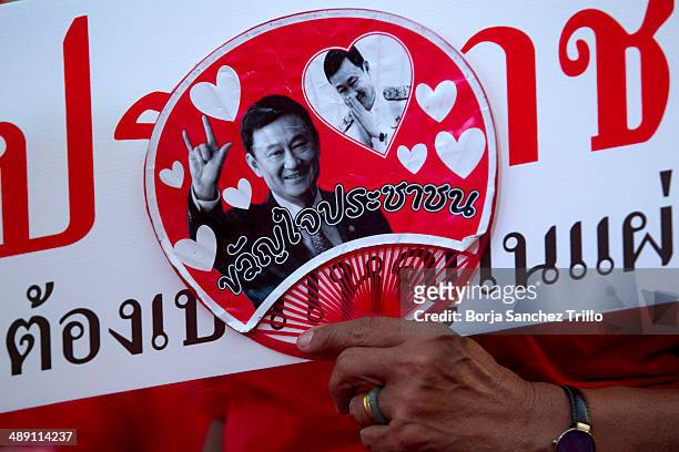 Pro-government red shirt supporters holds a portrait of former Thai Prime Minister, Thaksin Shinawatra, during a large rally on the outskirts of the...