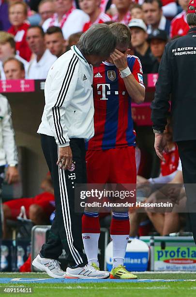 An injured Bastian Schweinsteiger of Bayern Muenchen talks to team doctor Hans-Wilhelm Mueller-Wohlfahrt as he is substituted during the Bundesliga...