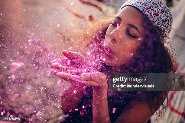 afro american teen girl blowing pink sparkling glitter outdoors - magenta stockfoto's en -beelden