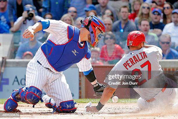 Jhonny Peralta of the St. Louis Cardinals slides safely into home plate as David Ross of the Chicago Cubs is unable to keep control of the ball...