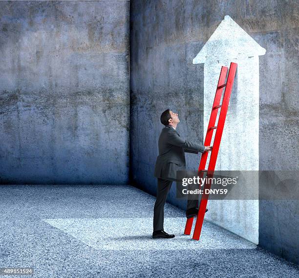 businessman climbing red ladder leaning against wall with arrow - men bulge stock pictures, royalty-free photos & images