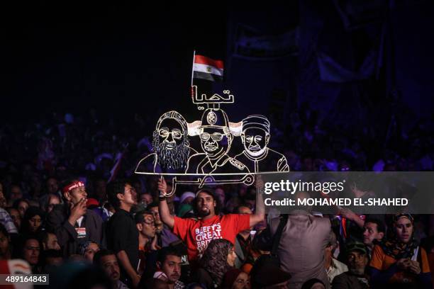 An Egyptian supporter of Egypt's former army chief Abdel Fattah al-Sisi holds a neon sign portraying him along with Pope Tawadros II , leader of...