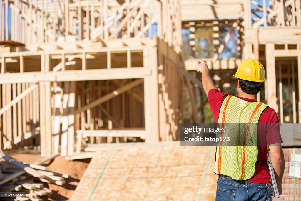 Construction worker busy working at job site. Framed building. Materials.