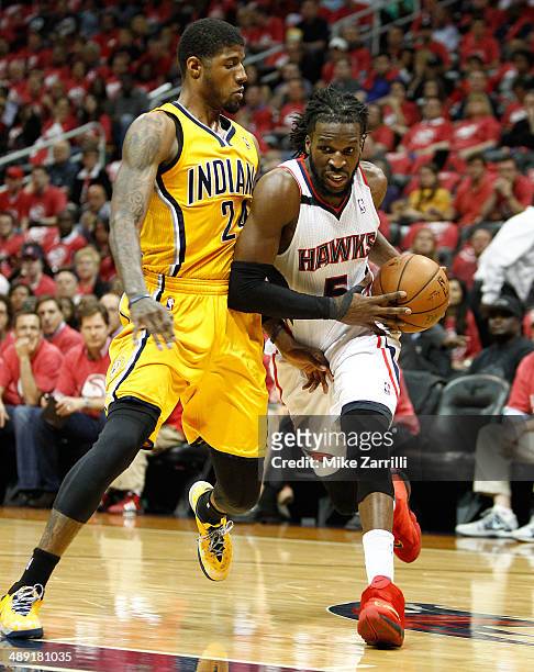 Forward DeMarre Carroll of the Atlanta Hawks dribbles while being defended by forward Paul George of the Indiana Pacers in Game Six of the Eastern...
