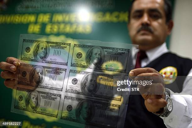 Police agent shows photolithographs after a gang dedicated to US currency forgery was dismantled in Lima on May 10, 2014. 1 000 counterfeit US...