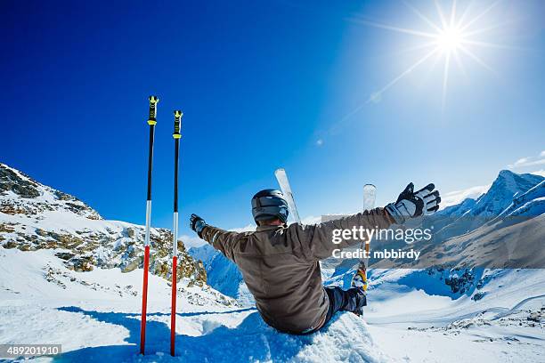 happy alpine skier sitting on the edge - ski poles stock pictures, royalty-free photos & images