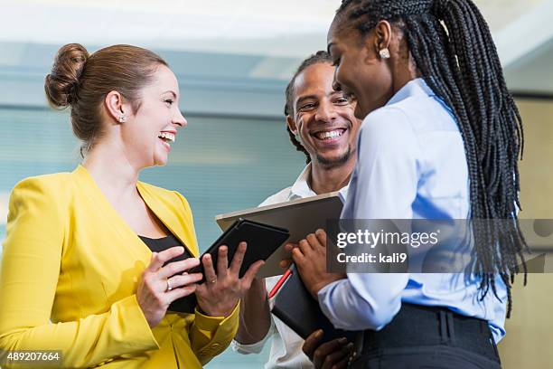 three multi-racial office workers talking and laughing - group of businesspeople standing low angle view stock pictures, royalty-free photos & images