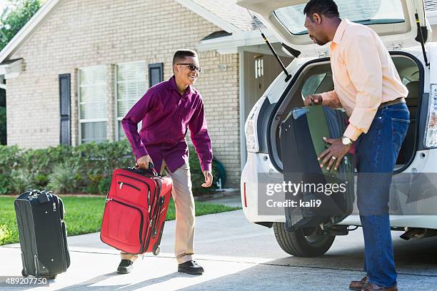 father and son loading suitcases into car - load lifter stock pictures, royalty-free photos & images