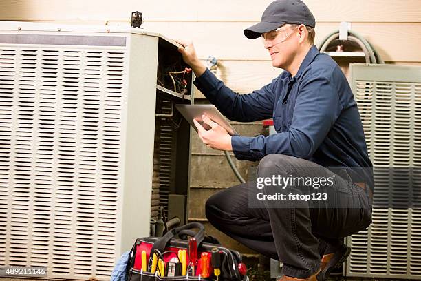 air conditioner repairman works on home unit. blue collar worker. - house inspection stock pictures, royalty-free photos & images