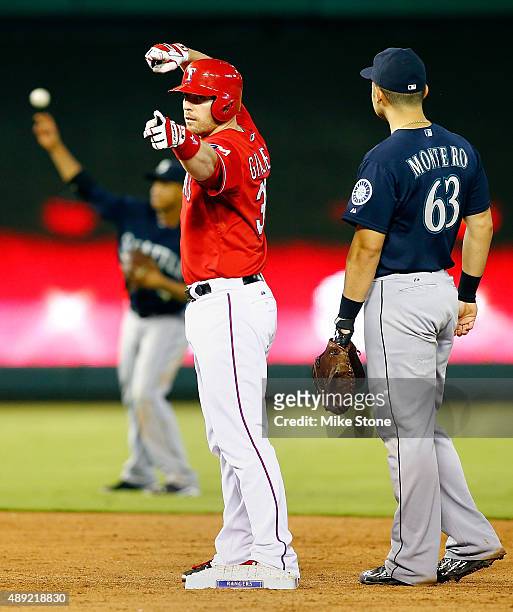 Chris Gimenez of the Texas Rangers points to the dugout after doubling in a run as Jesus Montero of the Seattle Mariners is near in the fifth inning...