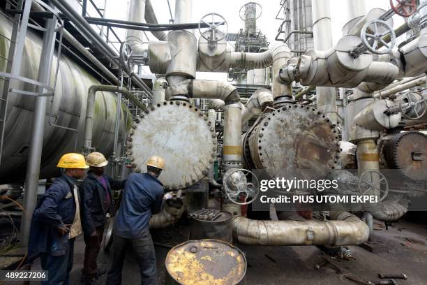 Picture taken on September 16, 2015 shows workers trying to tie a pipe of the first refinery in Nigeria, which was built in 1965 in oil rich Port...