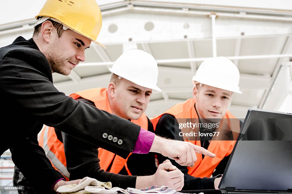 Architect pointing plans on laptop
