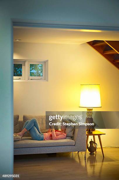 teen girl working/playing on her tablet computer - lying on back girl on the sofa stock pictures, royalty-free photos & images