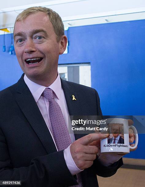 Leader of the Liberal Democrats Tim Farron holds up a coffee mug that features a picture of him as he visits the trade and exhibition stands on the...