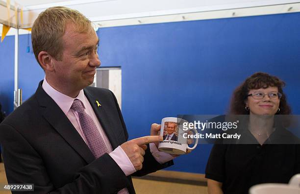 Leader of the Liberal Democrats Tim Farron holds up a coffee mug that features a picture of him as he visits the trade and exhibition stands on the...