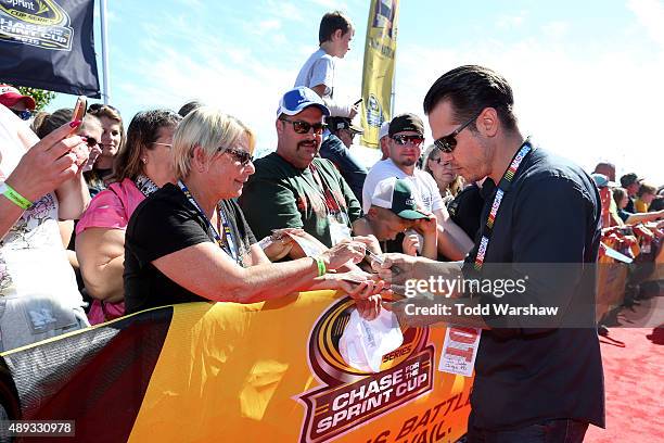Actor Jon Seda of the tv show Chicago P.D. Signs autographs prior to the NASCAR Sprint Cup Series myAFibRisk.com 400 at Chicagoland Speedway on...