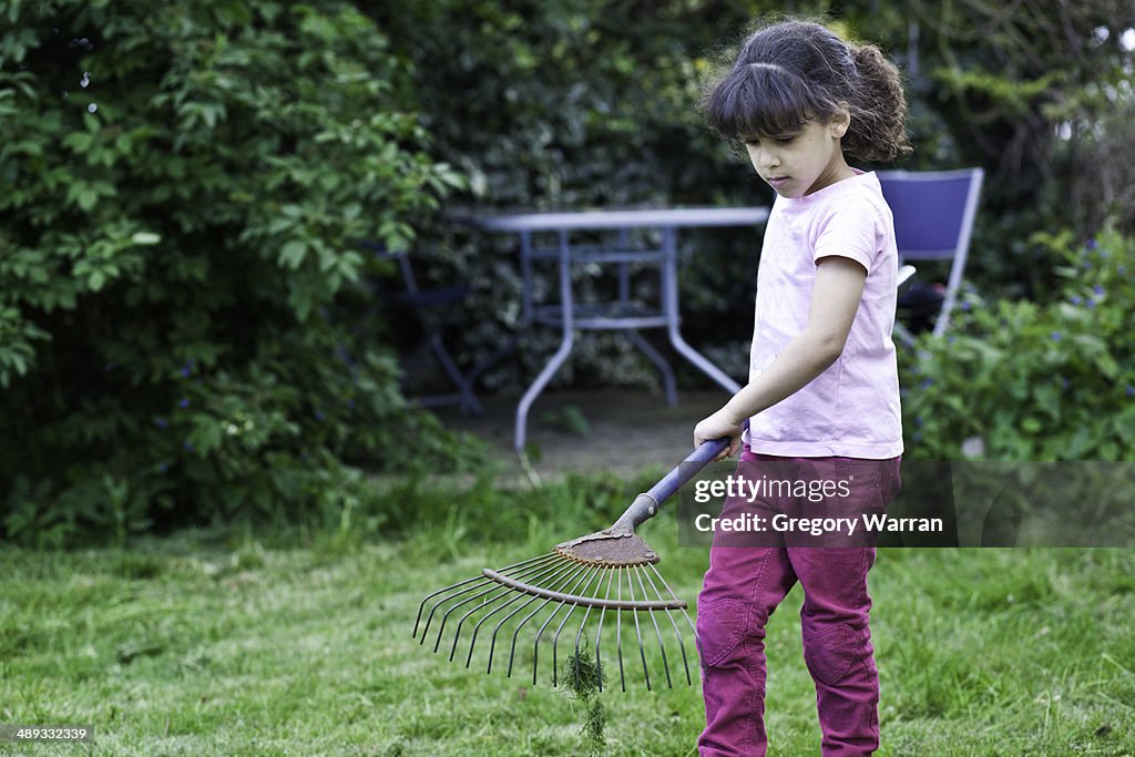 Girl helping to rake the garden