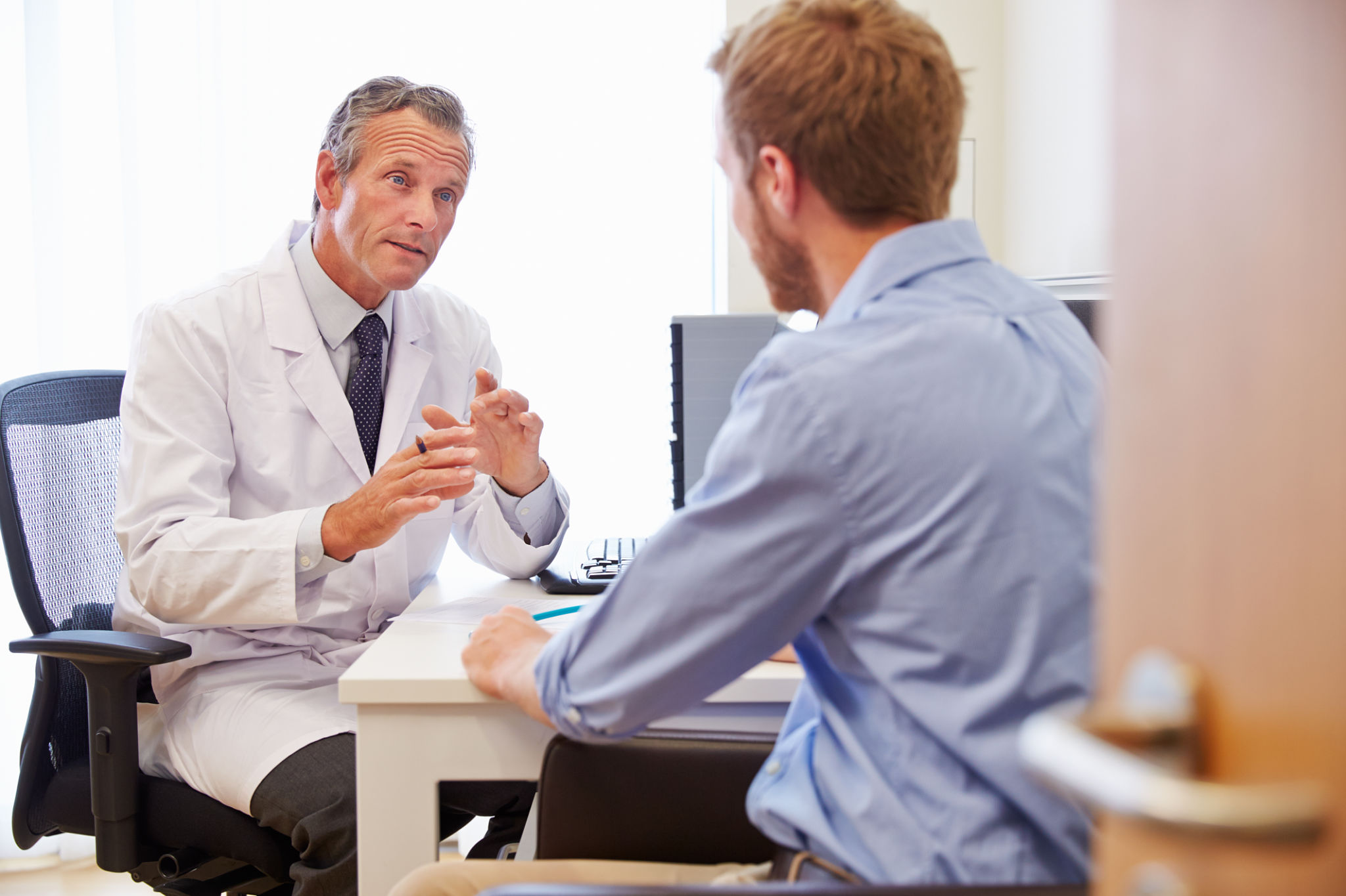 Male Patient Having Consultation With Doctor In Office Male Patient Having Consultation With Doctor In Office