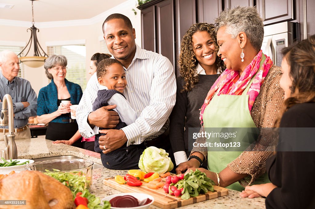 Thanksgiving: Multi-ethnic family, friends gather in kitchen to prepare meal.