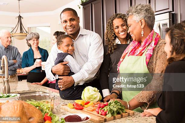 thanksgiving:  multi-ethnic family, friends gather in kitchen to prepare meal. - multi generation family christmas stock pictures, royalty-free photos & images