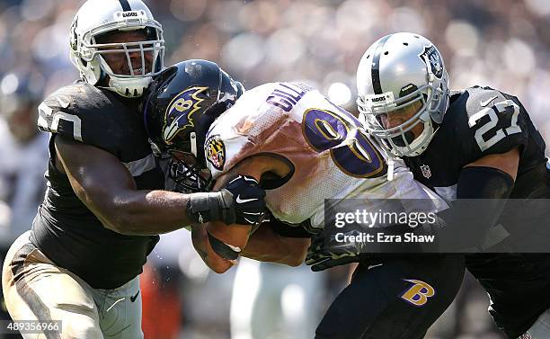 Crockett Gillmore of the Baltimore Ravens carries for a touchdown against the blocks of Taylor Mays of the Oakland Raiders and Curtis Lofton of the...