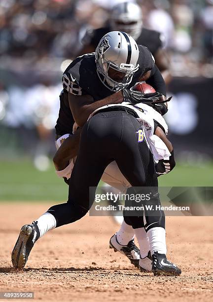 Clive Walford of the Oakland Raiders collides with the block of Kendrick Lewis of the Baltimore Ravens in the second quarter at Oakland-Alameda...