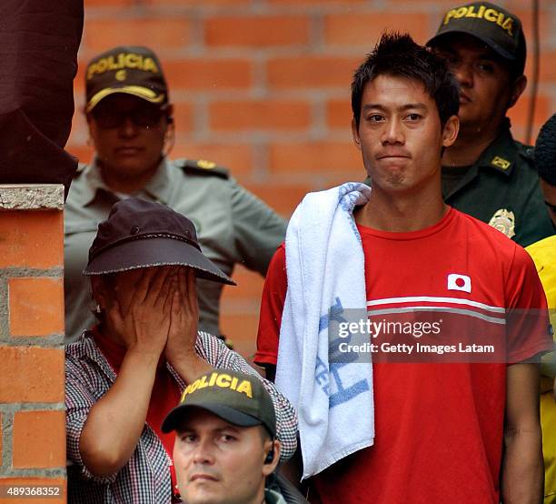 Kei Nishikori watches escorted by police officers the Davis Cup World Group Play-off singles match between Alejandro Falla of Colombia and Taro...