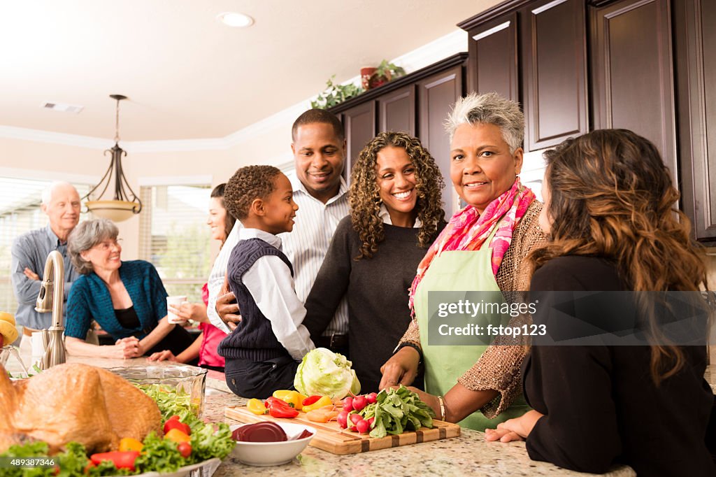 Thanksgiving:  Multi-ethnic family, friends gather in kitchen to prepare meal.