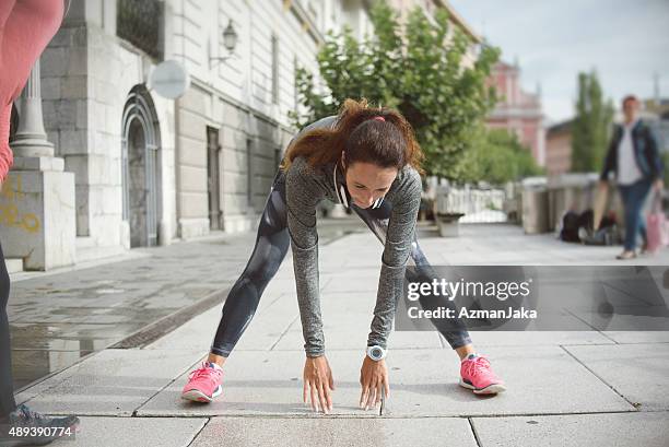 frau dehnen in der stadt, bevor sie joggen - zehenspitzen berühren stock-fotos und bilder