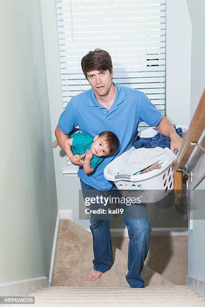 father multitasking, carrying baby and laundry upstairs - carrying laundry stock pictures, royalty-free photos & images