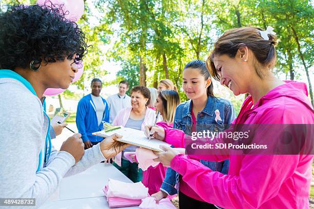 una gran diversidad de personas registrarte para caridad carrera contra el cáncer de mama - community events fotografías e imágenes de stock