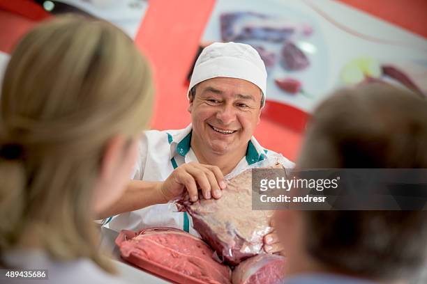 butcher serving customers at the butchery - slagerij stockfoto's en -beelden