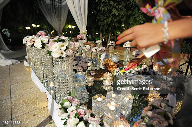 An Iranian woman lights candles on an elaborate table laid out with flowers and glass ornaments for a luxury wedding with mixed dancing and removal...