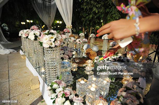 An Iranian woman lights candles on an elaborate table laid out with flowers and glass ornaments for a luxury wedding with mixed dancing and removal...