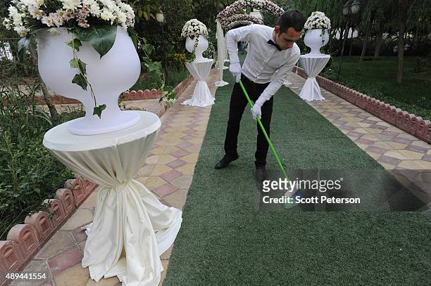 The carpet is swept by a white-gloved server as Iranian families take part in a luxury wedding with mixed dancing and removal of headscarves, at a...