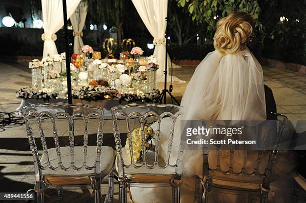 An Iranian bride sits beside her bouquet at a luxury wedding with mixed dancing and removal of headscarves, at a private garden tailor-made for the...