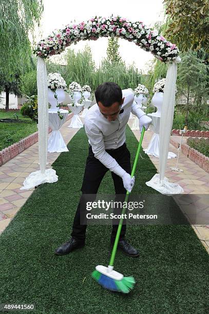 The carpet is swept by a white-gloved server as Iranian families take part in a luxury wedding with mixed dancing and removal of headscarves, at a...