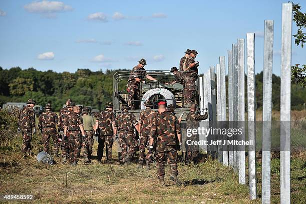 Hungarian soldiers erect a fence at a border point between Croatia and Hungary where migrants are being transported by bus through to Austria on...