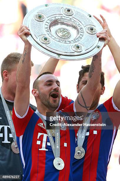 Diego Contento of Bayern Muenchen lifts the Bundesliga championship trophy in celebration after the Bundesliga match between Bayern Muenchen and VfB...