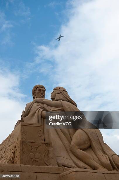 An aircraft flies over a sand sculpture at Zhujiajian Town in Putuo District on Septemebr 21, 2015 in Zhoushan, Zhejiang Province of China. All those...