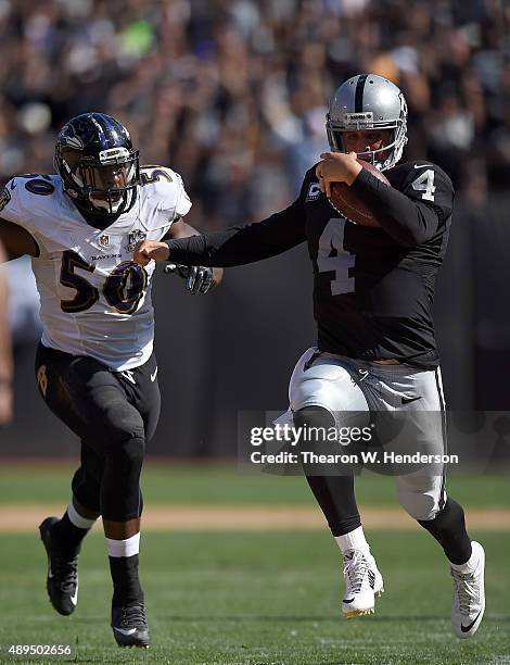 Derek Carr of the Oakland Raiders runs with the ball while pursued by Albert McClellan of the Baltimore Ravens in the third quarter at the O.co...