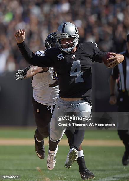Derek Carr of the Oakland Raiders runs with the ball while pursued by Albert McClellan of the Baltimore Ravens in the third quarter at the O.co...